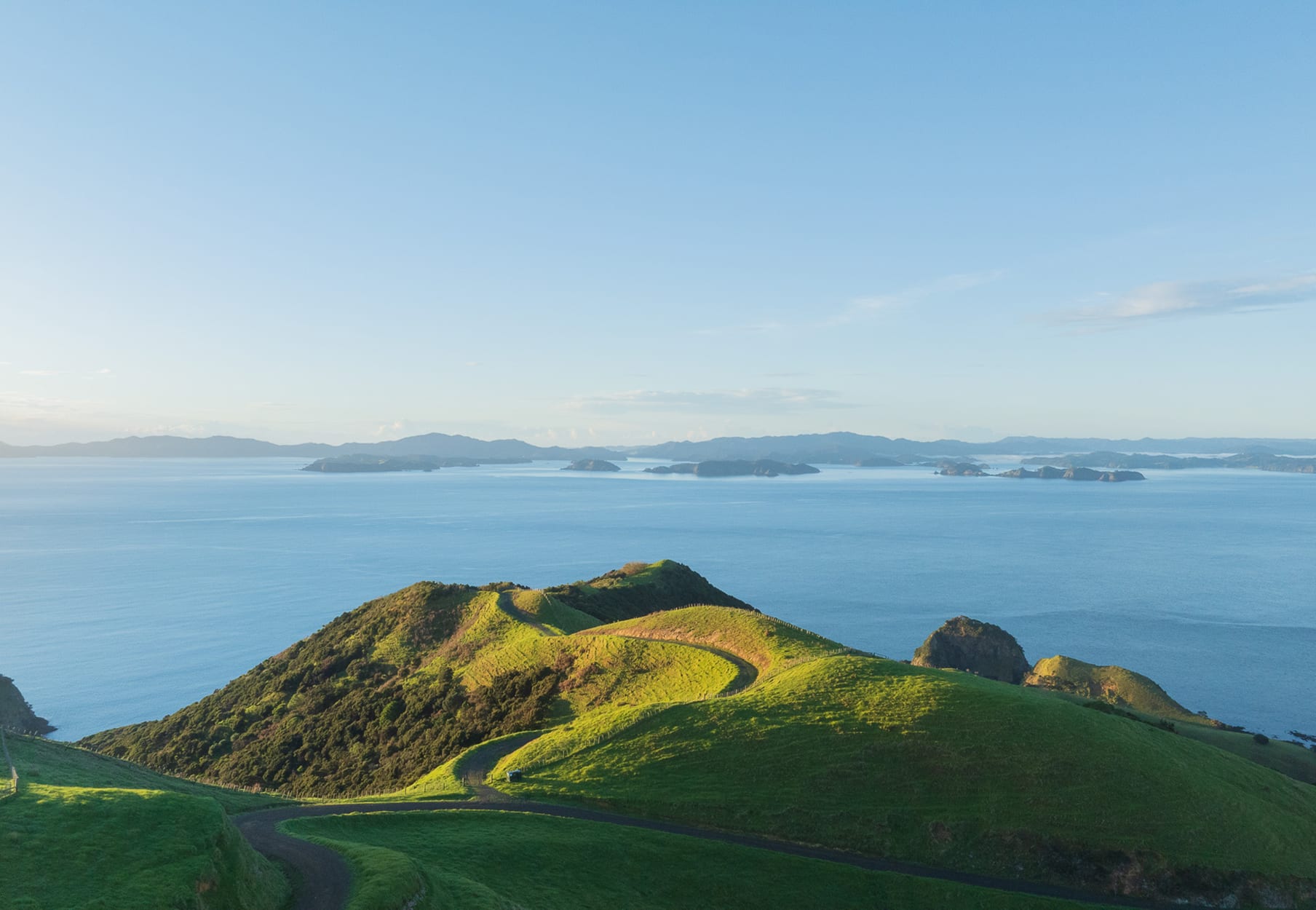 Winding private road tracing the crest of the hills with the Bay of Islands beyond