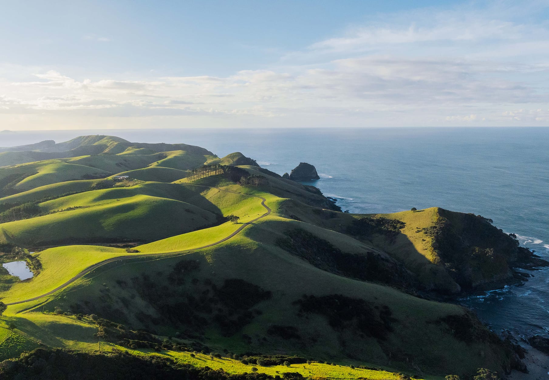 Aerial overview of Mataka Station — green hills, private road, dam and coastal headlands