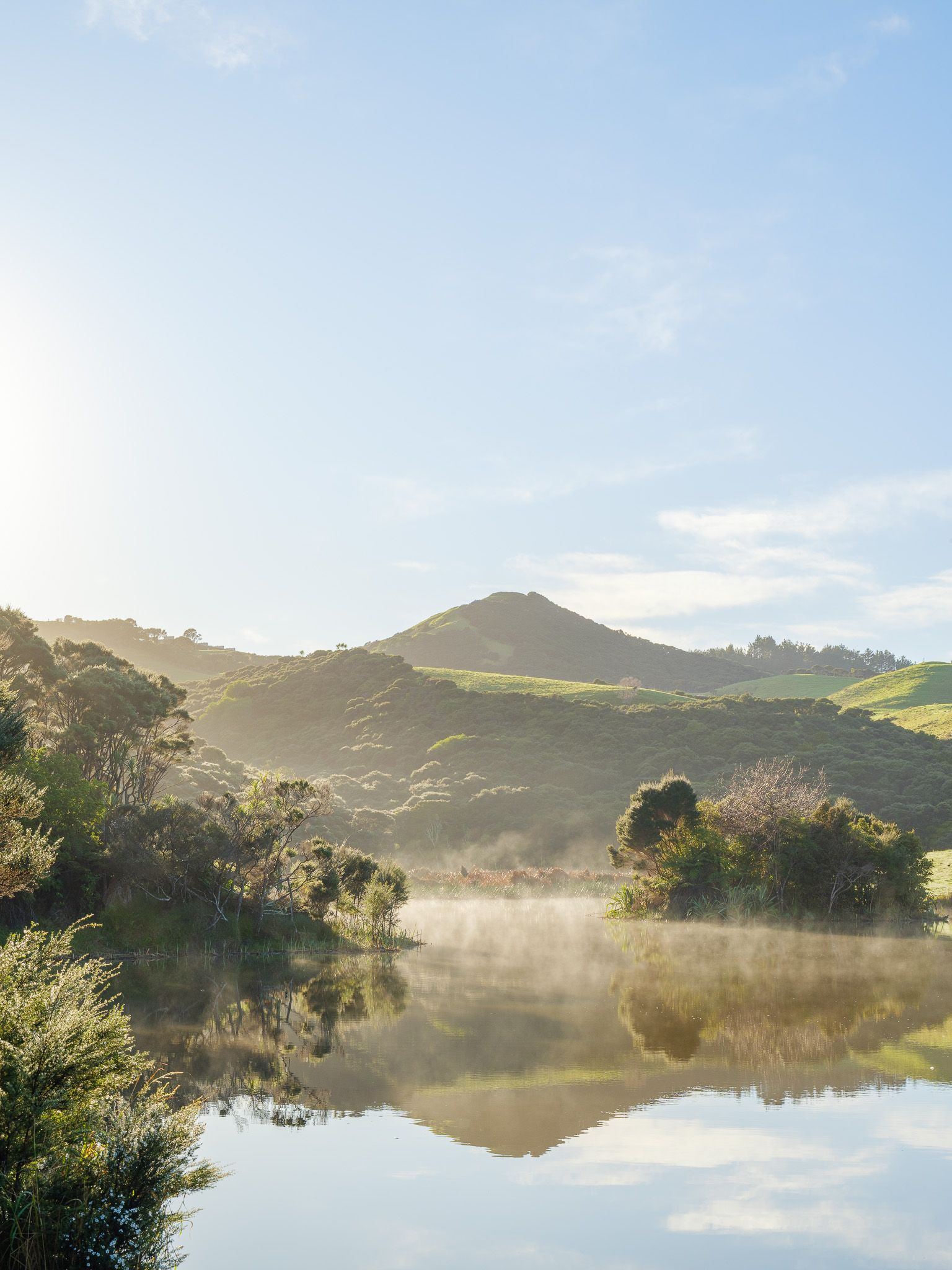 Still water below the hills, mist lifting off the surface